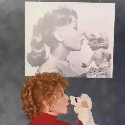 A woman with a white sock puppet and a picture of her and the puppet above her.